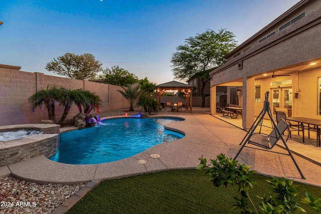 pool at dusk with a patio, an in ground hot tub, pool water feature, ceiling fan, and a gazebo