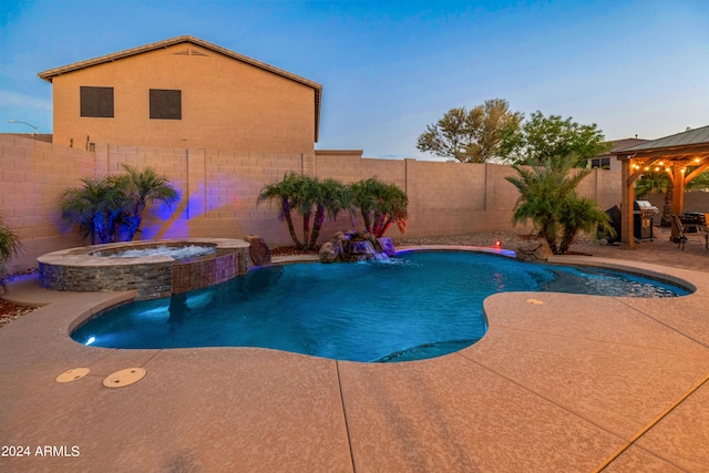 pool at dusk with a patio area, pool water feature, and an in ground hot tub