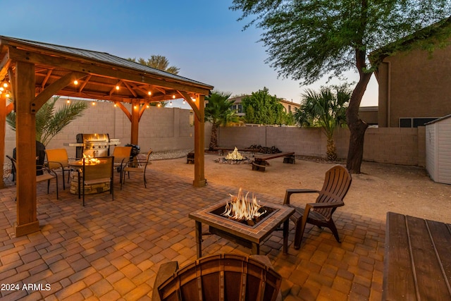 patio terrace at dusk featuring a gazebo, a grill, and a fire pit