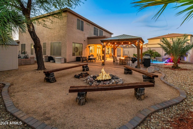 back house at dusk featuring a gazebo and an outdoor fire pit