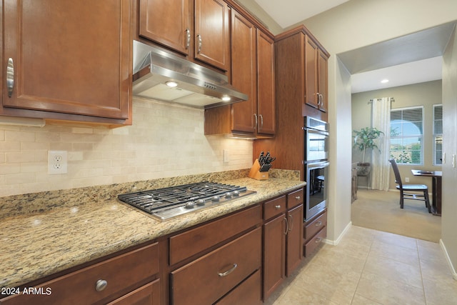 kitchen with backsplash, light tile patterned flooring, stainless steel appliances, and light stone counters