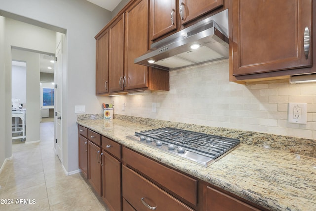 kitchen featuring decorative backsplash, light stone counters, stainless steel gas cooktop, and light tile patterned flooring