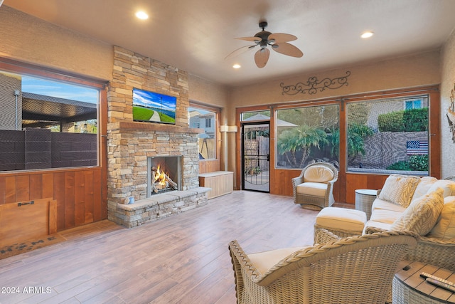 living room featuring wood walls, ceiling fan, hardwood / wood-style flooring, and a fireplace