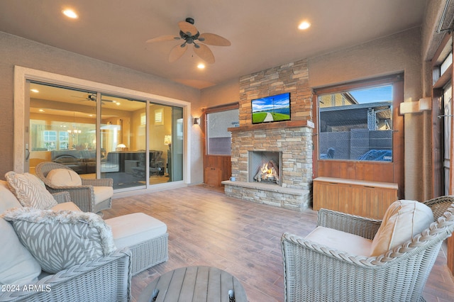 living room with wood-type flooring, ceiling fan, and a fireplace