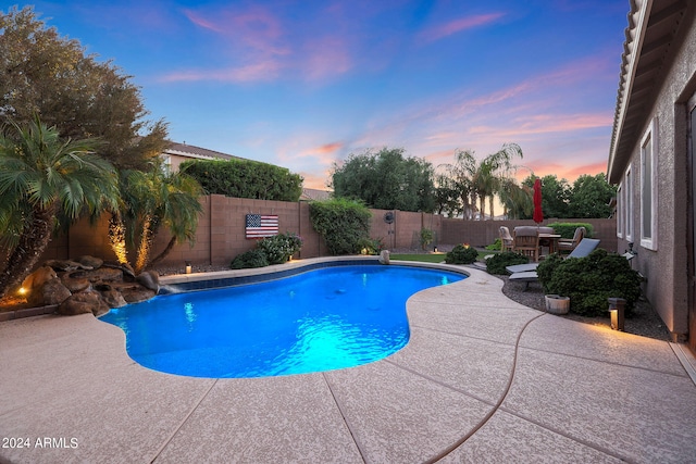 pool at dusk with a patio area