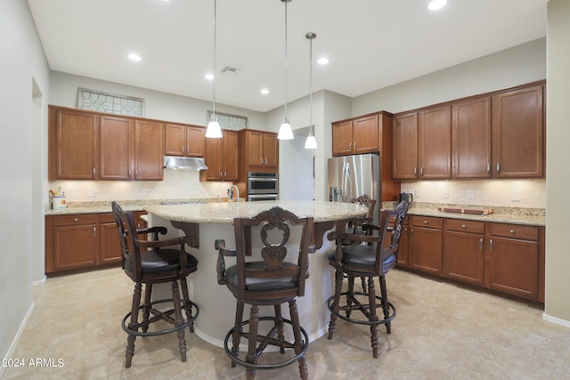 kitchen with pendant lighting, a kitchen island with sink, sink, a kitchen bar, and light stone countertops