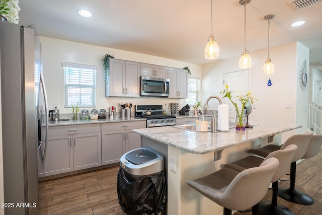 16425 W Latham St, Goodyear, AZ 85338 - kitchen featuring appliances with stainless steel finishes, a breakfast bar, wood finished floors, a kitchen island with sink, and a sink