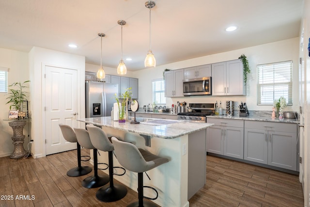 16425 W Latham St, Goodyear, AZ 85338 - kitchen with stainless steel appliances, dark wood finished floors, light stone counters, gray cabinets, and recessed lighting