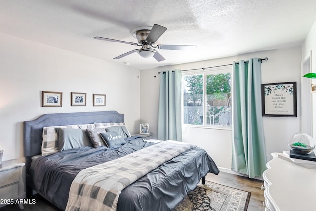 bedroom featuring a textured ceiling, a ceiling fan, and wood finished floors