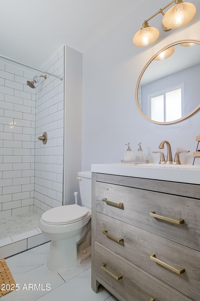 full bathroom featuring a tile shower, marble finish floor, toilet, and vanity