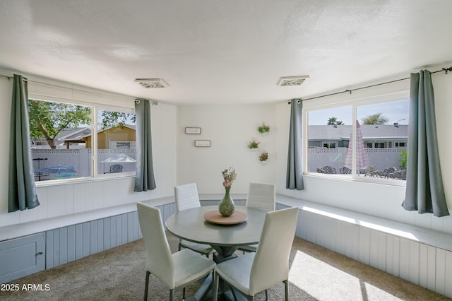 dining room with visible vents, a healthy amount of sunlight, a textured ceiling, and carpet