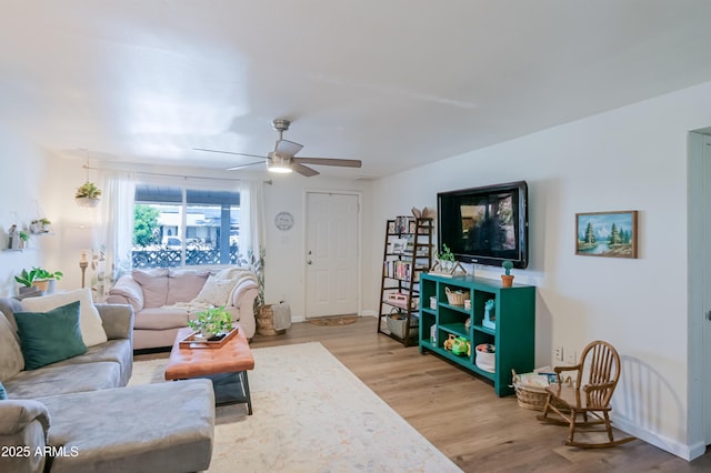 living room with ceiling fan, baseboards, and wood finished floors