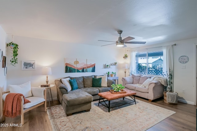 living area featuring wood finished floors, baseboards, and ceiling fan