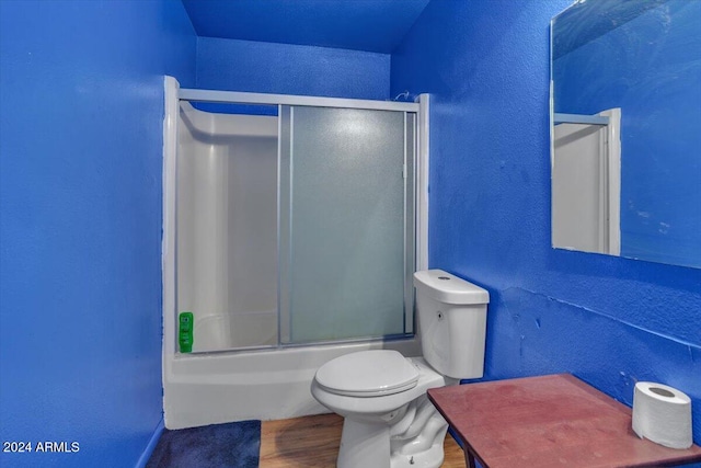 bathroom featuring combined bath / shower with glass door, hardwood / wood-style flooring, and toilet