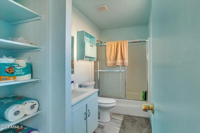 full bathroom featuring vanity, bath / shower combo with glass door, and toilet