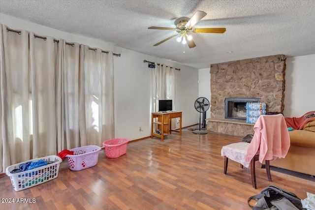 interior space featuring ceiling fan, wood-type flooring, a textured ceiling, and a fireplace