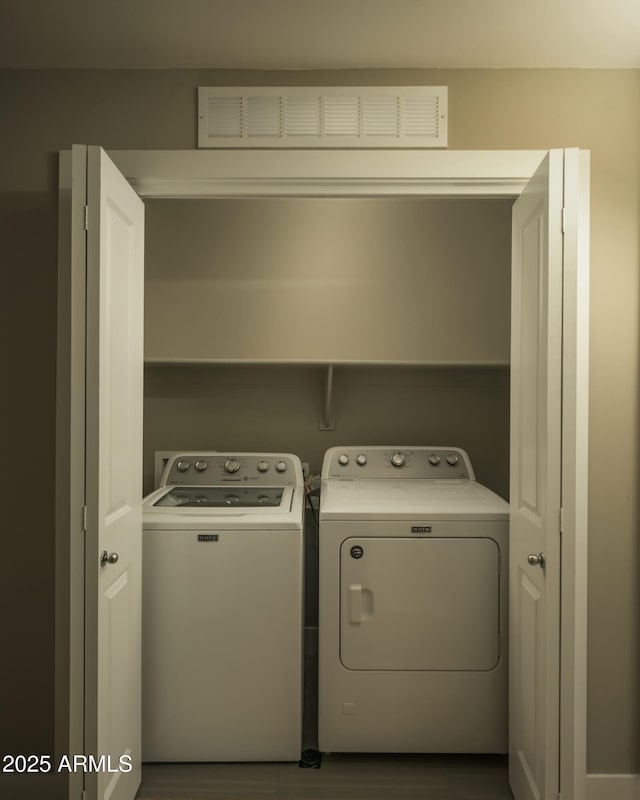 laundry area featuring laundry area, visible vents, washer and clothes dryer, and wood finished floors