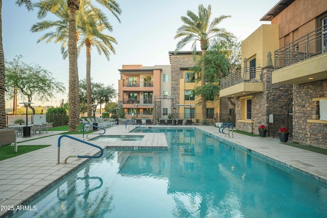 pool at dusk featuring a patio area and a community pool