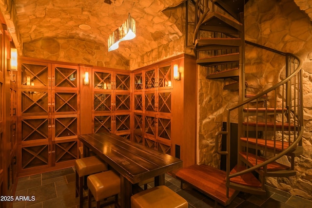 wine area featuring vaulted ceiling and stone tile flooring