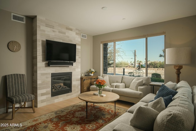 living room with visible vents, wood finished floors, and a tile fireplace