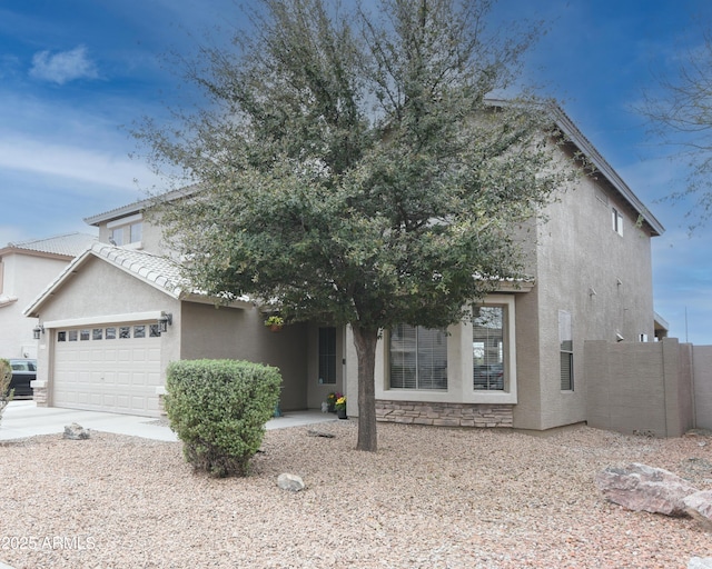 view of front of property with a tile roof, stucco siding, concrete driveway, an attached garage, and fence