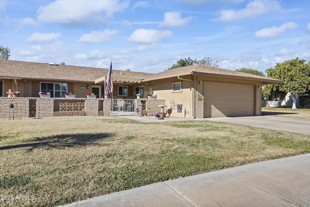 ranch-style home featuring a front lawn, covered porch, and a garage