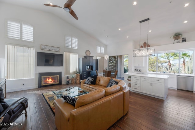 living room with ceiling fan, dark hardwood / wood-style floors, sink, and high vaulted ceiling