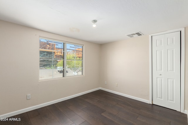 unfurnished bedroom with dark hardwood / wood-style flooring and a closet