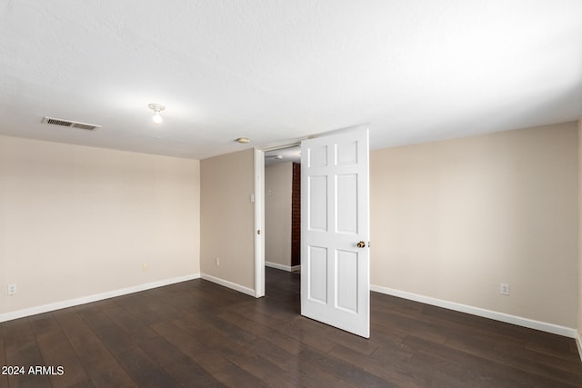 unfurnished bedroom featuring brick wall and dark wood-type flooring