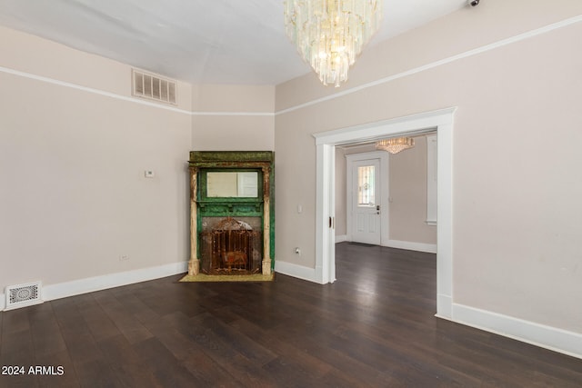 unfurnished living room featuring an inviting chandelier and dark wood-type flooring