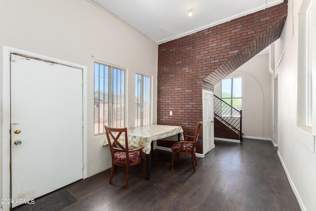 dining space with brick wall, dark hardwood / wood-style floors, and crown molding