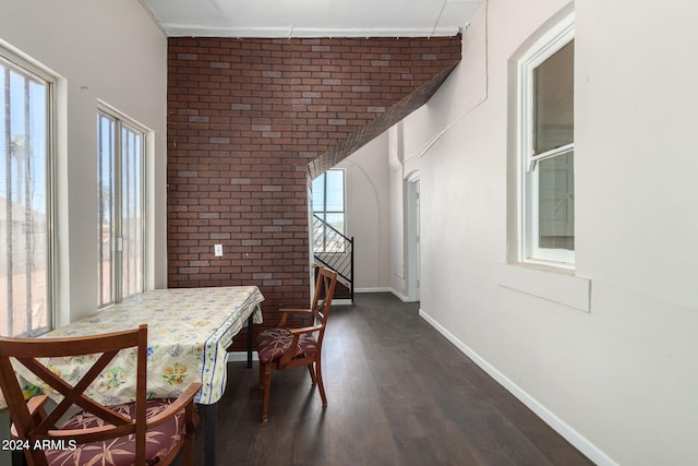 dining space featuring dark hardwood / wood-style floors, brick wall, and a wealth of natural light