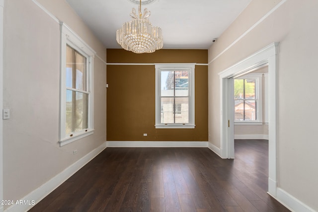 spare room with an inviting chandelier and hardwood / wood-style flooring