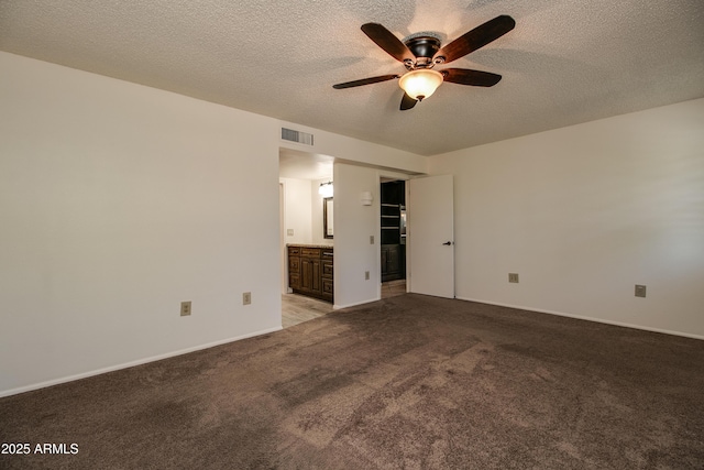 spare room with a ceiling fan, visible vents, baseboards, a textured ceiling, and light colored carpet