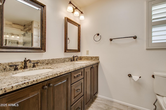 full bath featuring double vanity, toilet, baseboards, and a sink
