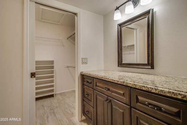 bathroom with baseboards, a spacious closet, wood finished floors, and vanity