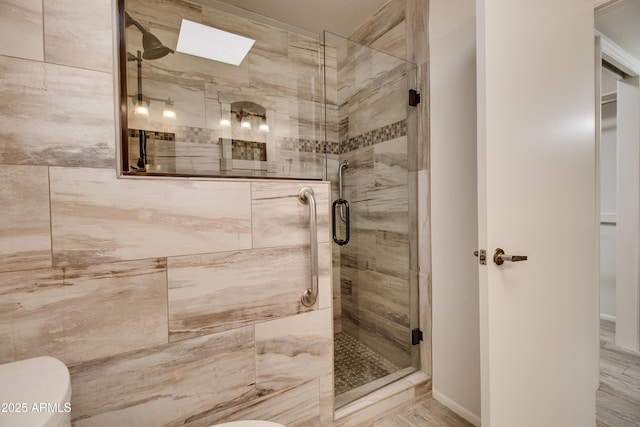 full bath with toilet, a stall shower, and a skylight