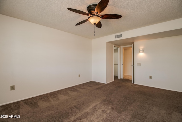 empty room featuring a ceiling fan, visible vents, dark colored carpet, and a textured ceiling