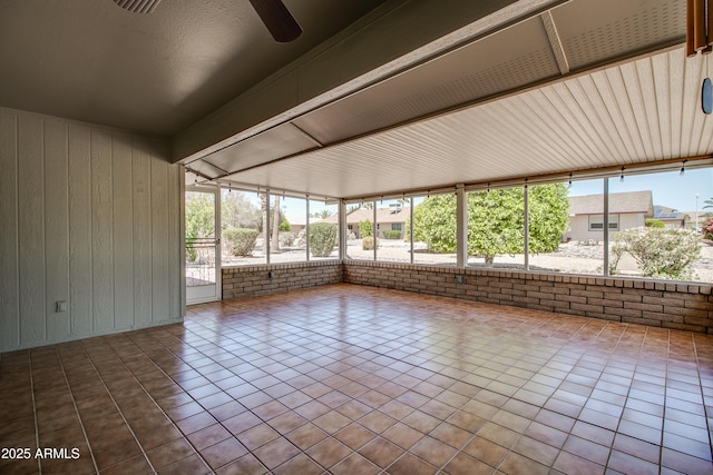 unfurnished sunroom with wood walls, tile patterned flooring, and brick wall