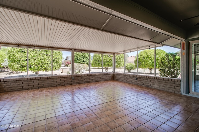unfurnished sunroom with tile patterned flooring and brick wall