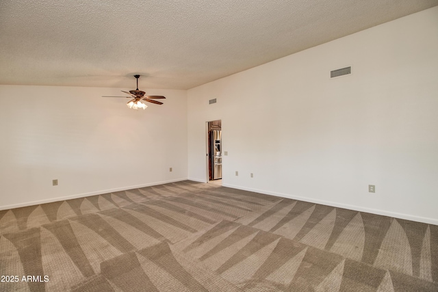 carpeted spare room featuring a textured ceiling, visible vents, ceiling fan, and baseboards