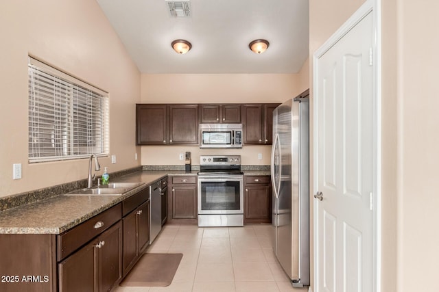 kitchen with light tile patterned flooring, appliances with stainless steel finishes, sink, and dark brown cabinets