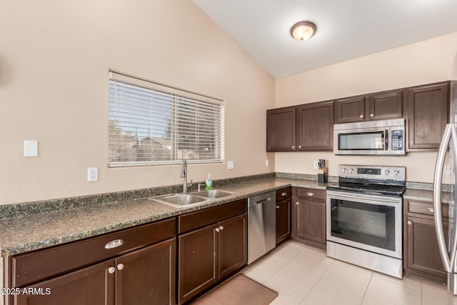 kitchen with light tile patterned flooring, lofted ceiling, sink, dark brown cabinetry, and stainless steel appliances