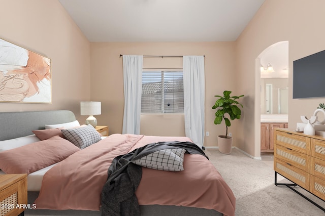 bedroom with light carpet, ensuite bath, and vaulted ceiling