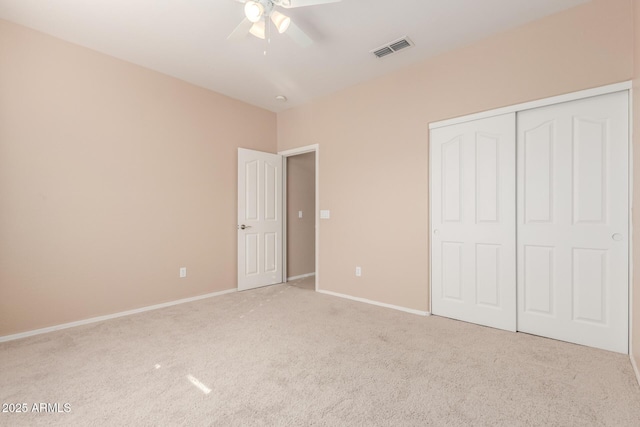 unfurnished bedroom with ceiling fan, light colored carpet, and a closet