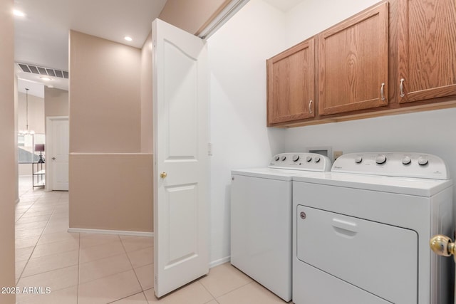 washroom featuring washer and dryer, light tile patterned floors, and cabinets