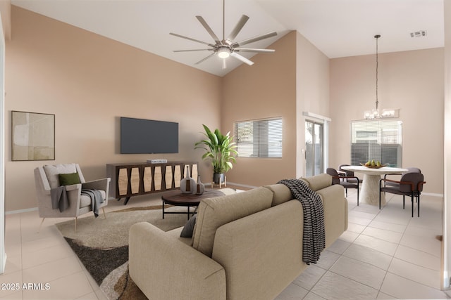 tiled living room featuring ceiling fan with notable chandelier and high vaulted ceiling