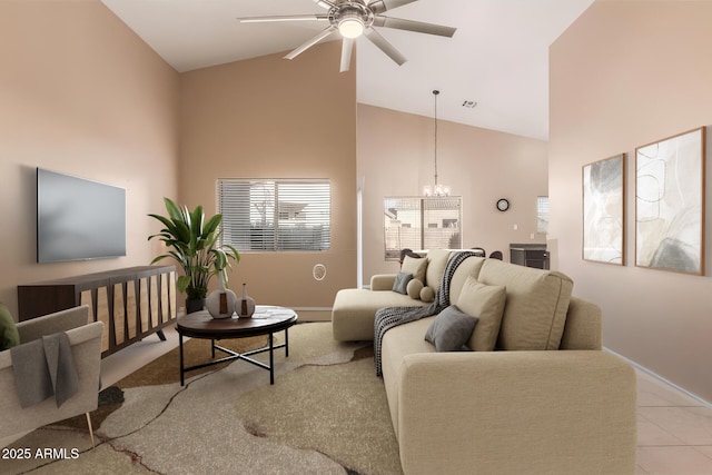 living room with light tile patterned flooring, ceiling fan with notable chandelier, and high vaulted ceiling