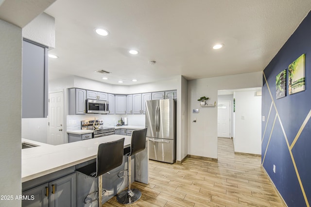 4162 W Sierra St, Phoenix, AZ 85029 - kitchen with stainless steel appliances, gray cabinetry, light wood-style floors, a peninsula, and baseboards