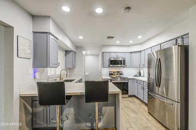 4162 W Sierra St, Phoenix, AZ 85029 - kitchen with appliances with stainless steel finishes, gray cabinets, a peninsula, light wood-type flooring, and light countertops